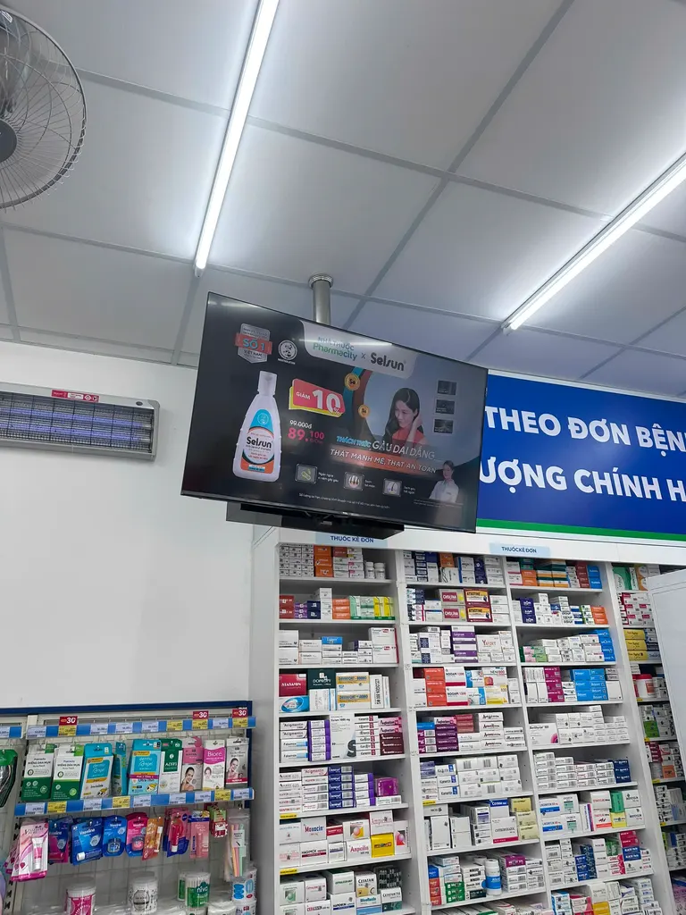 Màn hình phát quảng cáo phía trên kệ thuốc tại cửa hàng Pharmacity